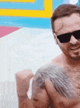 a shirtless man with a tattoo on his chest wearing sunglasses .