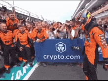 a race car driver stands in front of a crowd holding a sign that says crypto.com