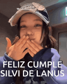 a girl wearing a baseball cap and a purple sweatshirt says feliz cumple silvi de lanus