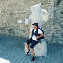 a man sits in front of a statue of a bear which says andy egger on the base
