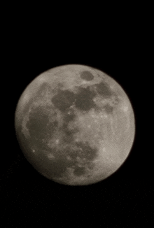 a full moon is visible in the night sky with a black background .