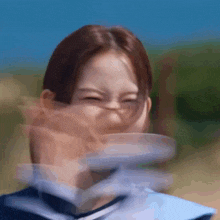 a woman in a school uniform is making a funny face while holding a plate in her hand .