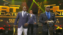 three men in suits are standing in front of a sign that says aew on it