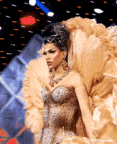 a woman in a gold dress with a crown on her head is on a stage