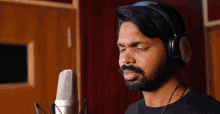 a man wearing headphones and a black shirt sings into a microphone