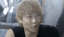 a close up of a young man with blonde hair making a face .