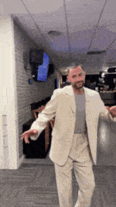 a man in a suit is standing in a hallway with his arms outstretched