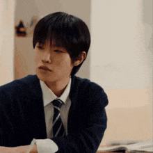 a young man wearing a sweater and tie is sitting at a desk .