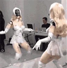 a woman in a white dress and gloves is dancing in front of a mirror .