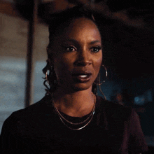a woman wearing hoop earrings and a necklace is looking at the camera