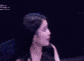 a woman in a blue dress is sitting in a chair with her hands folded .