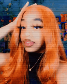 a woman with long orange hair is wearing a black top and a necklace