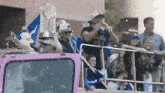 a man is holding a trophy on top of a pink truck .