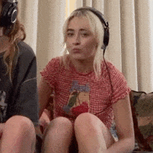 a young woman wearing headphones is sitting on a couch .