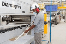a man is working on a machine in a factory wearing headphones and a mask .