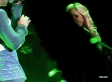 a man is singing into a microphone while a woman is standing behind him