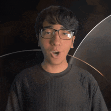 a man wearing glasses and an onyx shirt looks at the camera