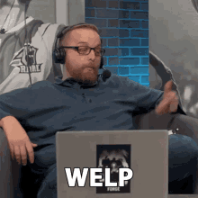 a man wearing headphones sitting in front of a laptop that says welp on it