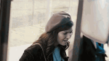 a woman wearing a beret is standing in front of a bus stop .