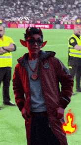 a man dressed as a devil stands on a field
