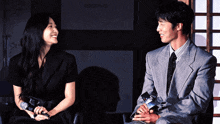 a man and a woman are sitting next to each other smiling and holding hands