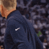 a man wearing a blue nike shirt stands in front of a crowd of people