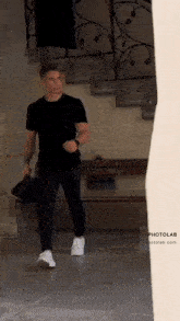 a man in a black t-shirt and black pants is walking down stairs .