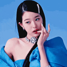 a woman wearing a blue top and a necklace with diamonds