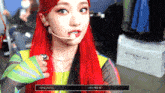 a woman with red hair is wearing a microphone and a givenchy box is in the background