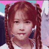 a girl with pigtails is wearing a microphone in her mouth