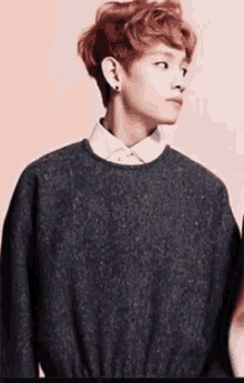 a young man with red hair is wearing a sweater and a white shirt