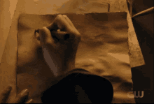 a person is writing on a piece of brown paper with a cw logo in the corner