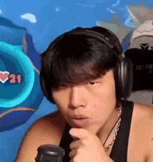 a man wearing headphones is sitting in front of a microphone and making a funny face .