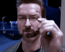 a man with a beard and glasses is holding a pair of glasses in his hand