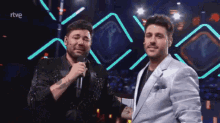two men are standing next to each other on a stage and one is crying while the other is smiling