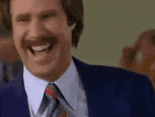 a man in a suit and tie is laughing and smiling .