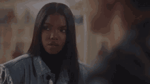 a woman in a denim jacket is looking at another woman in a locker room .