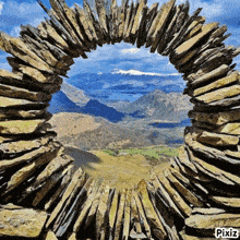 a view of a mountain valley through a stone arch