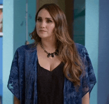 a woman wearing a black top and a blue kimono is standing in front of a blue wall
