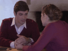 a man in a red sweater and a woman in a purple shirt are holding hands