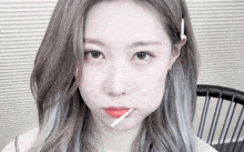 a girl with gray hair is holding a candy stick in her mouth