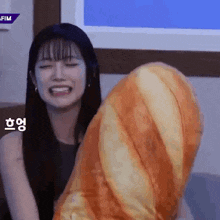 a woman is smiling while holding a stuffed bread roll .