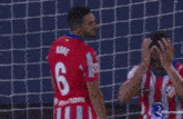 a group of soccer players are standing in front of a goal and one of them is holding his head .