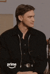 a man wearing a black jacket is sitting in front of an amazon prime ad