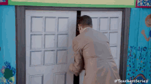 a man in a suit is opening a door to a room .