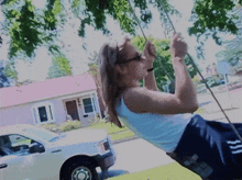 a woman in a white tank top is swinging on a rope