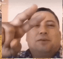 a man is making a peace sign with his fingers .