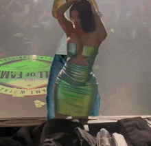 a woman in a green dress is standing in front of a sign that says l of fam