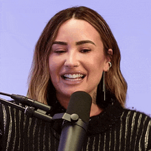 a woman is smiling in front of a microphone and has a nose ring