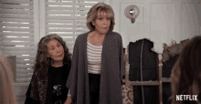 two older women standing next to each other with a netflix logo behind them